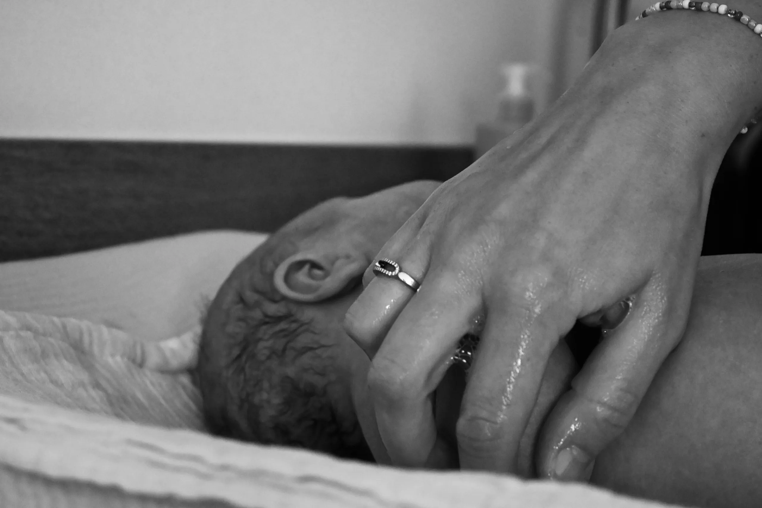 La main d’un parent posée sur la tête du nouveau-né endormi