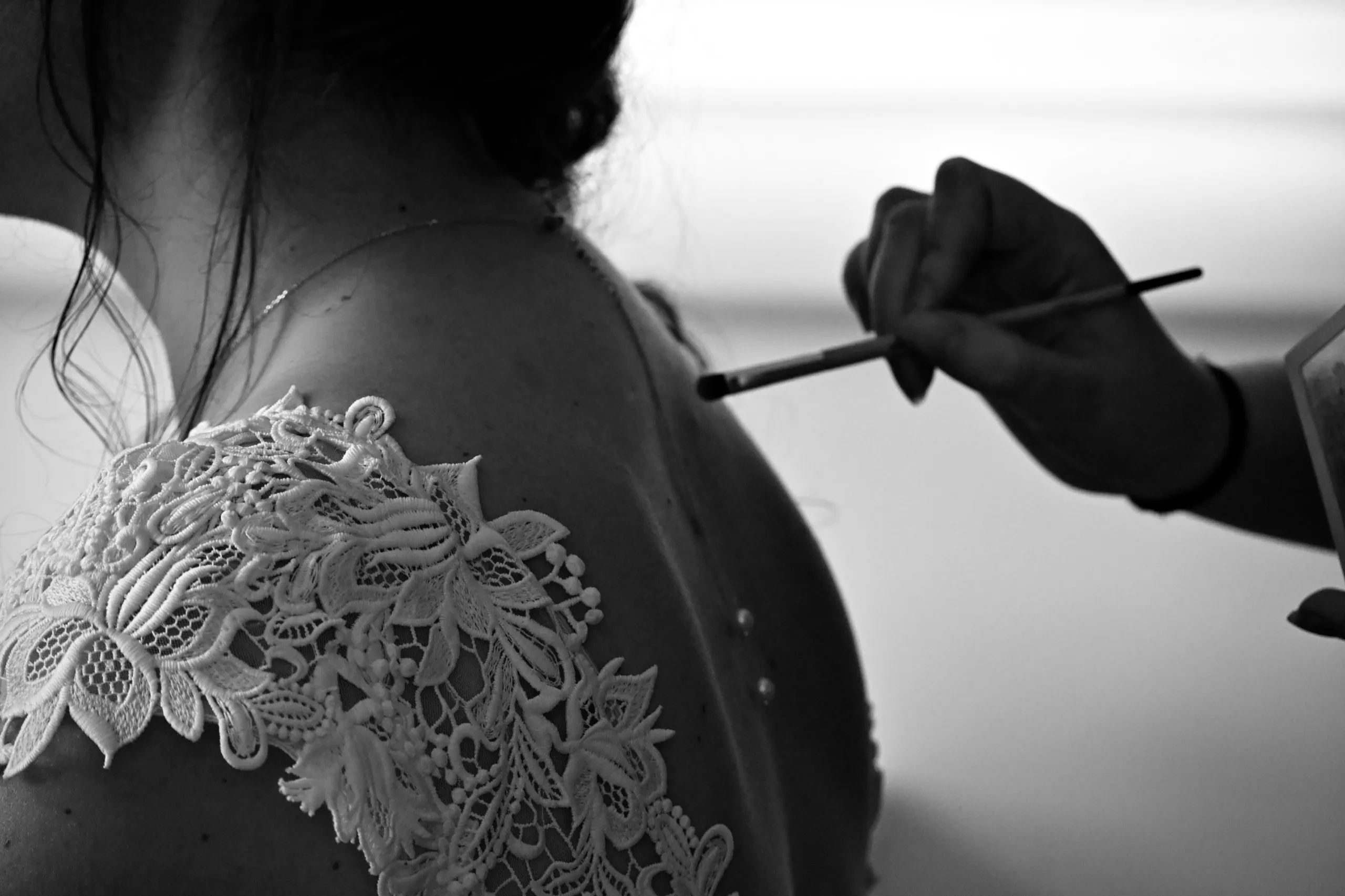 Détail de la robe en dentelle de la mariée pendant la mise en beauté