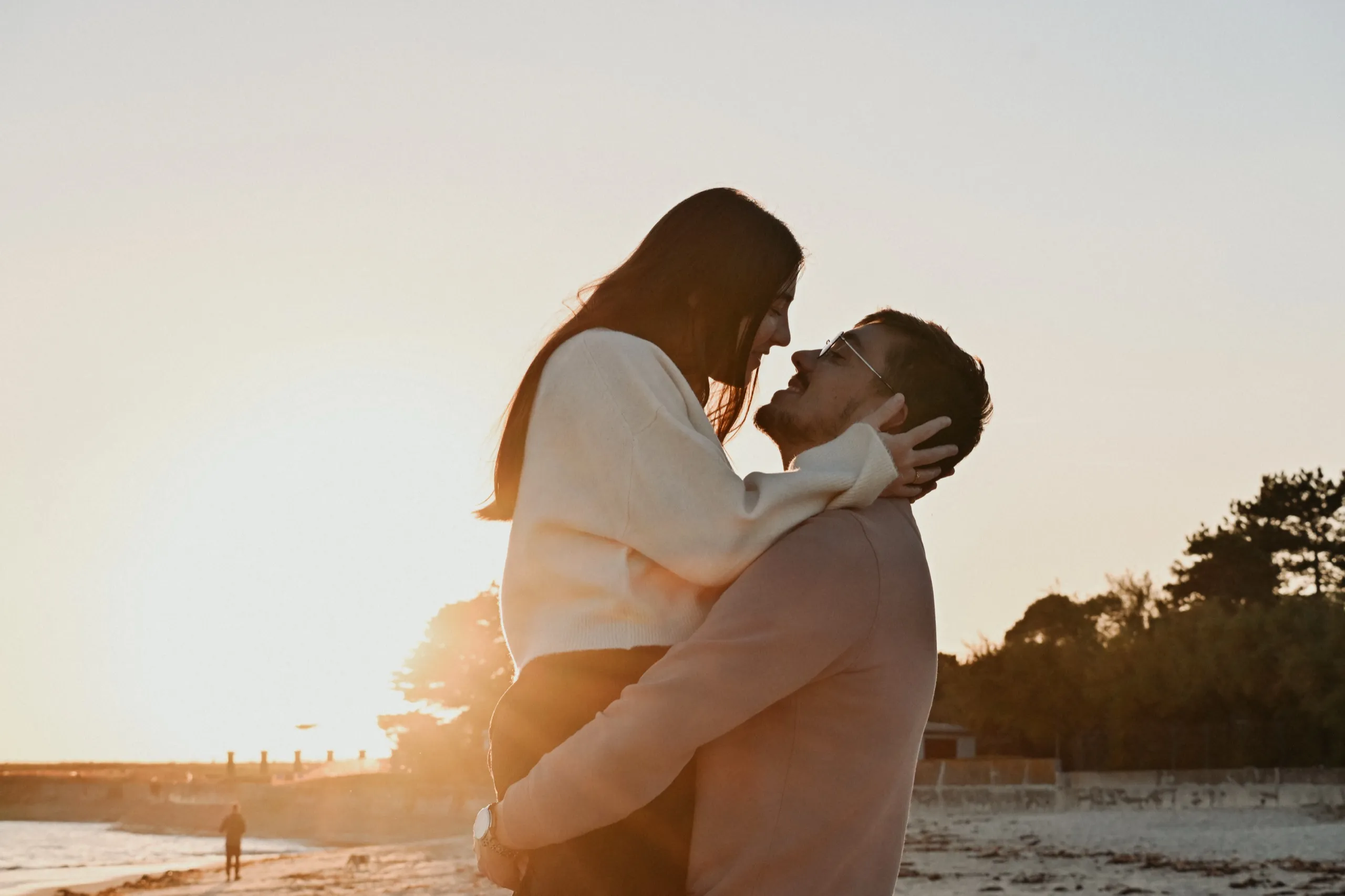 Un couple enlacé sur la plage au coucher du soleil