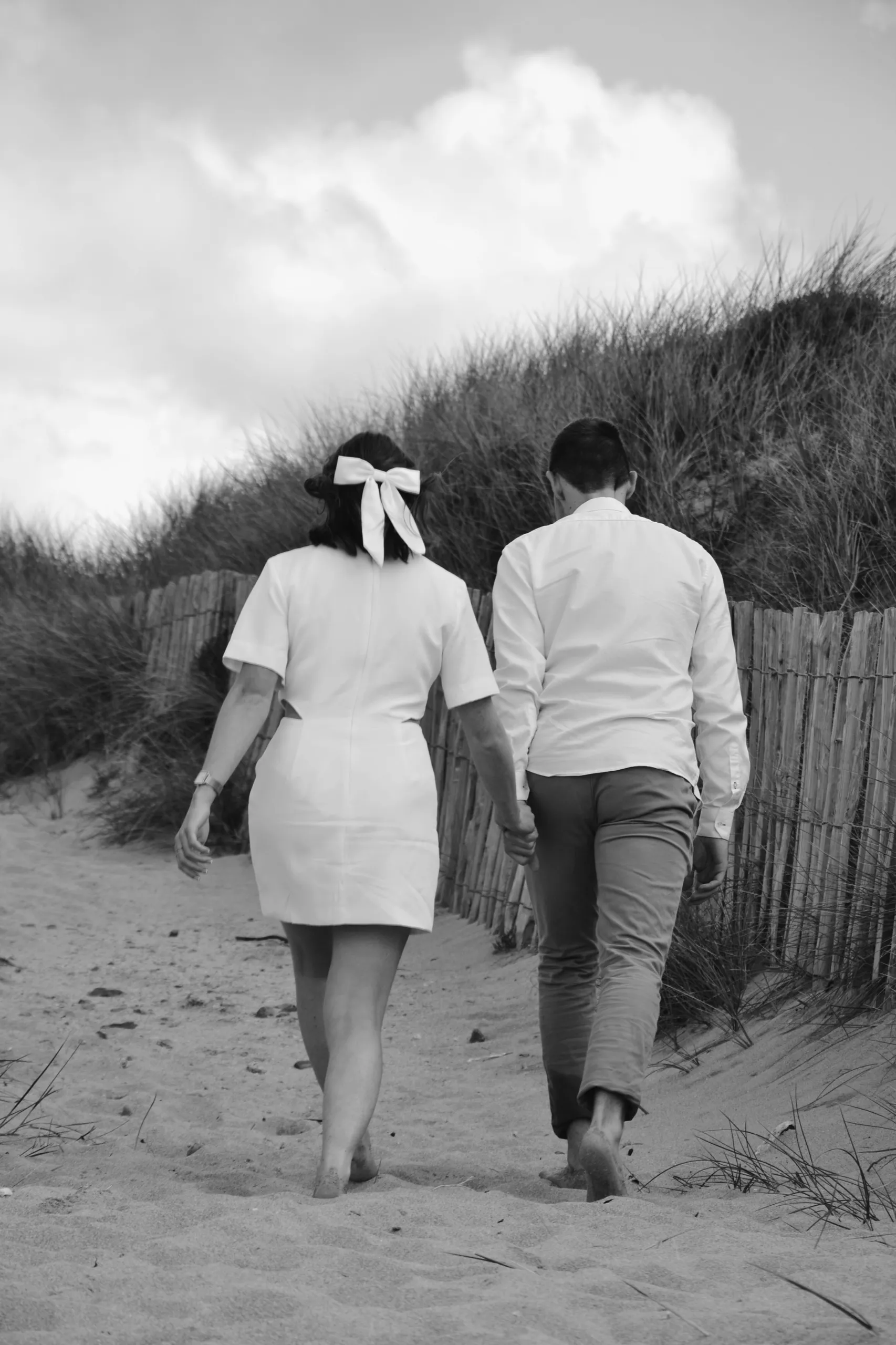 Un couple traverse la dune pour rejoindre la plage