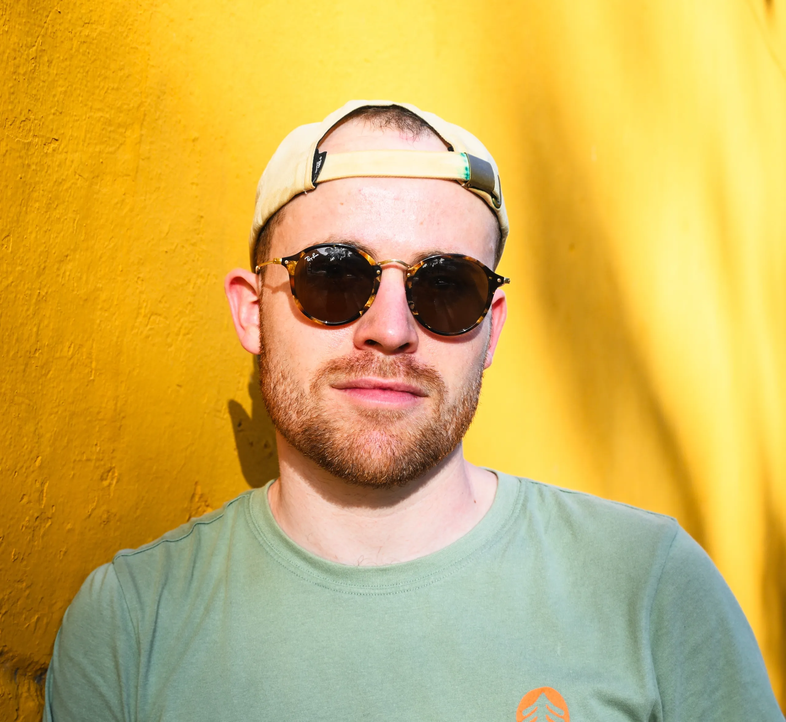 Portrait d’un homme à lunettes devant un mur jaune, au Mexique