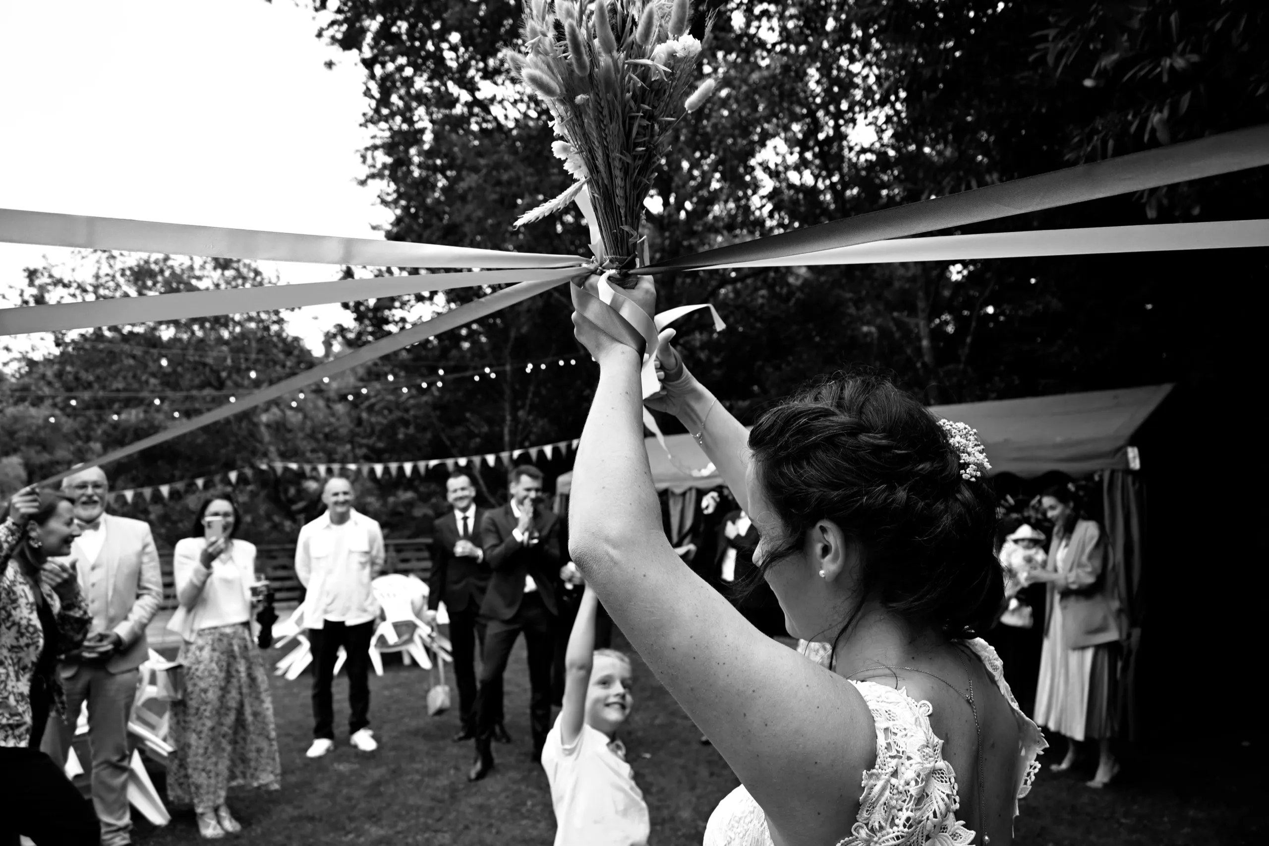 La mariée lève son bouquet au milieu des invités