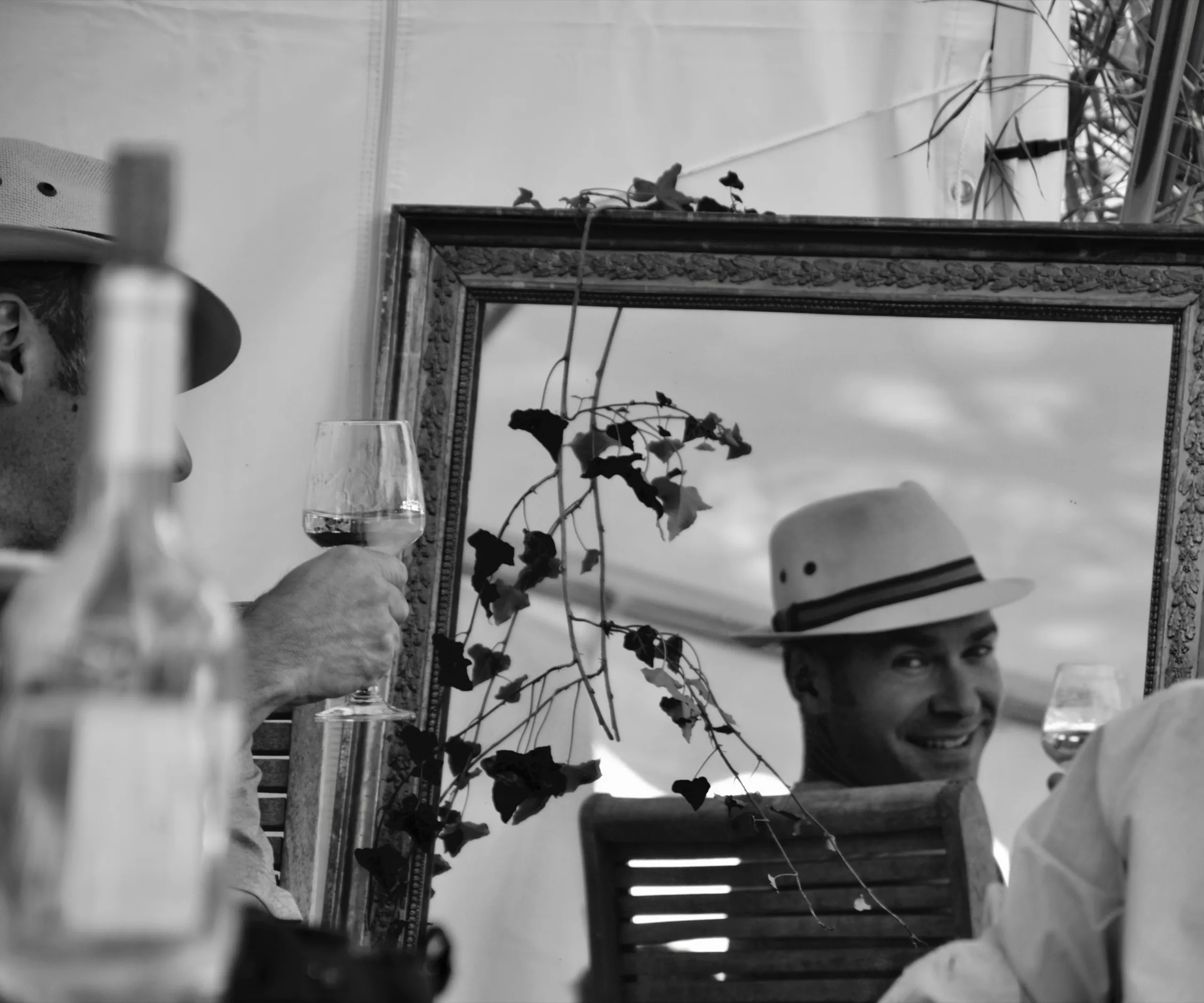 Un homme au chapeau, reflété dans un miroir, en noir et blanc