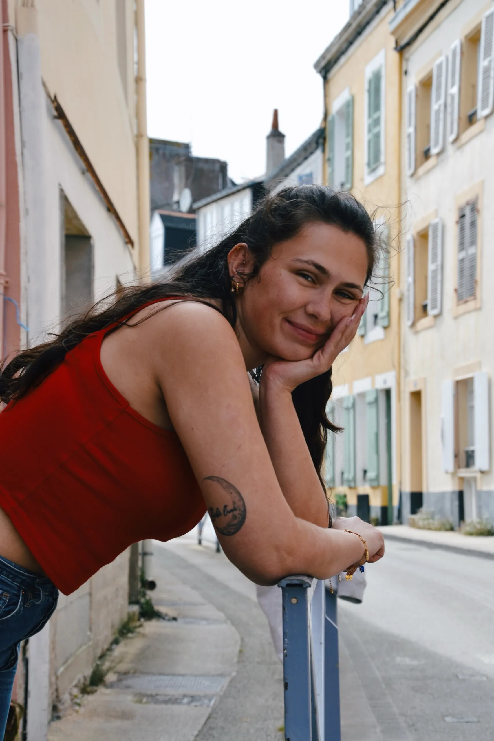 Portrait d’une jeune femme accoudée à une rambarde dans une rue colorée