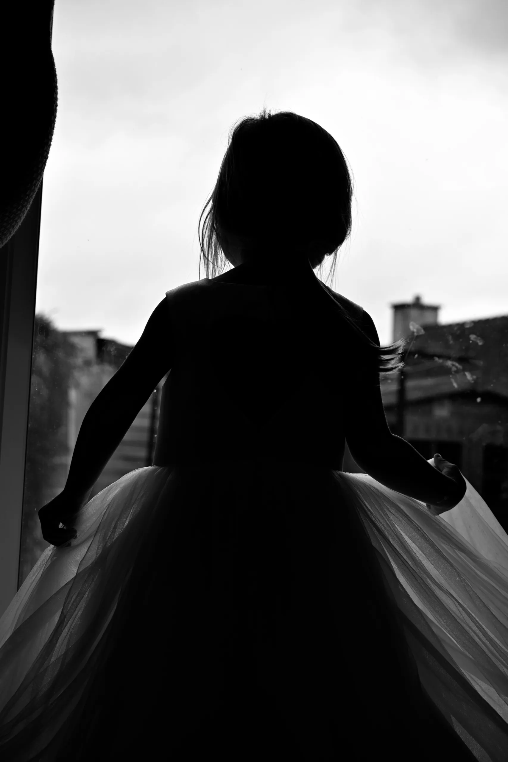 Silhouette d’une mariée devant une fenêtre, sa robe en mouvement